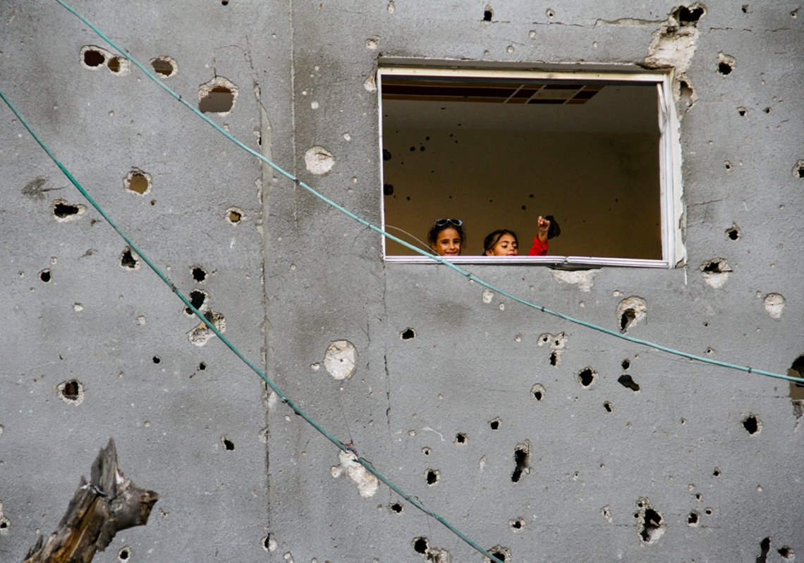 أطفال فلسطينيون ينظرون من نافذة منزلهم في غزة خلال عيد الفطر